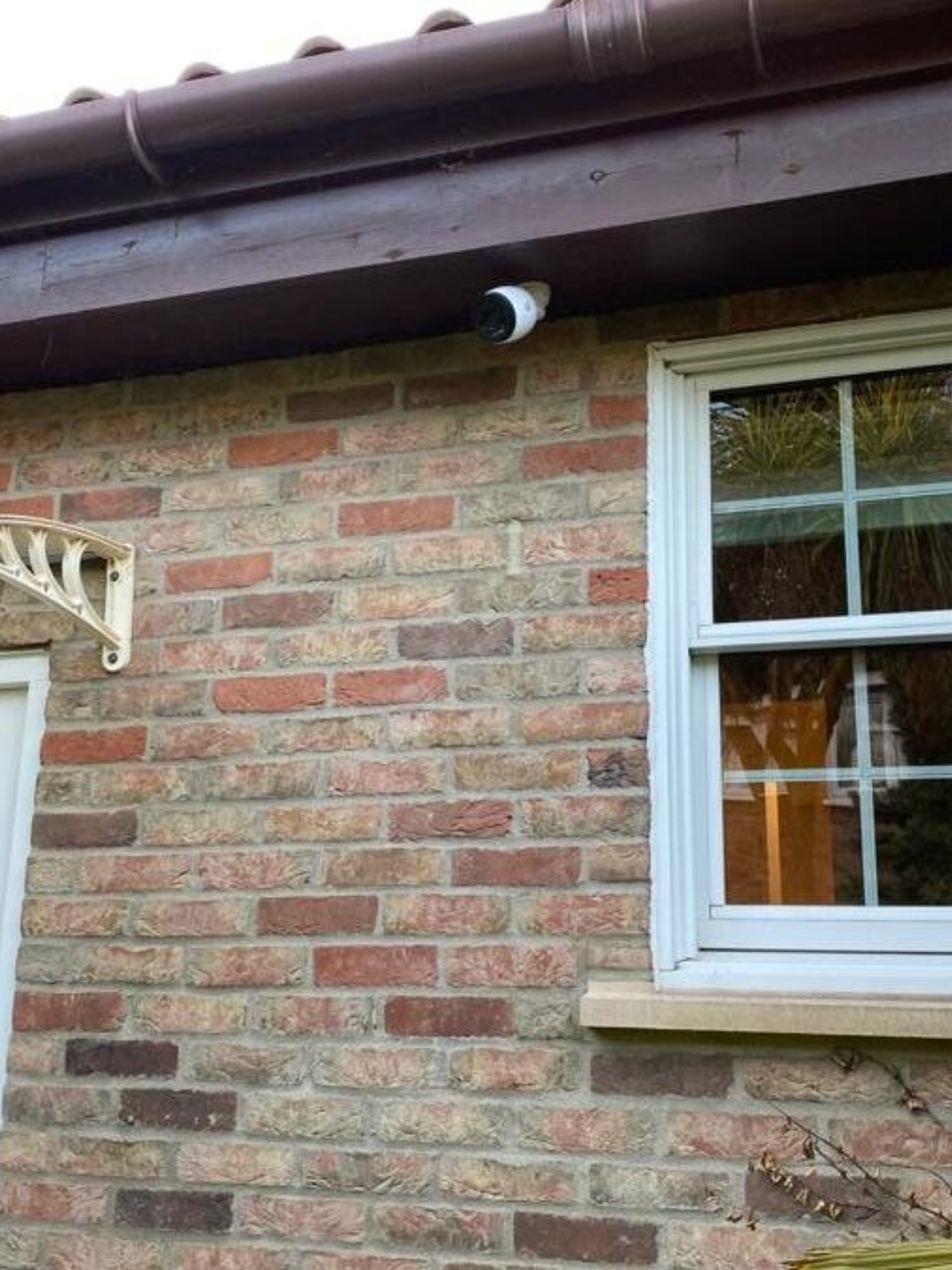 UniFi Security camera mounted on the side of a house pointing downwards