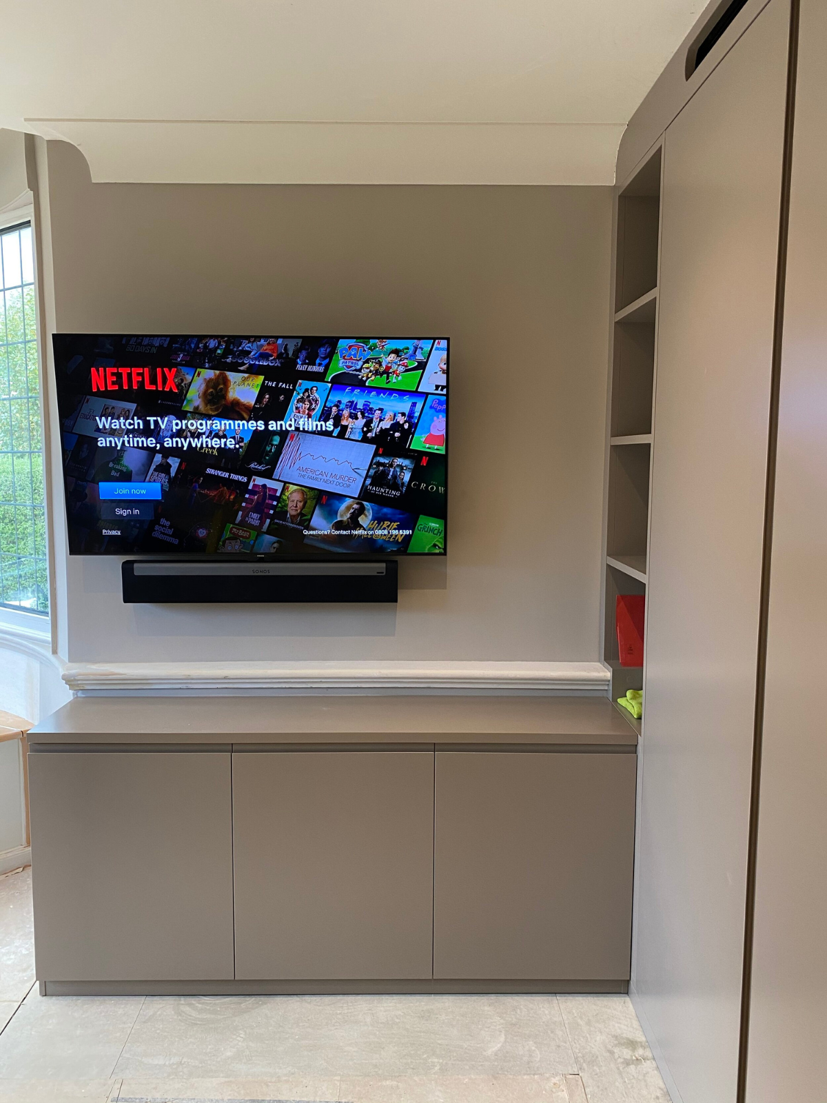 Smart OLED TV showing Netflix mounted on the wall with Sonos soundbar