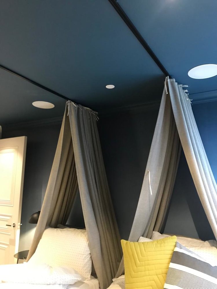 Bedroom with in-ceiling speakers above twin beds