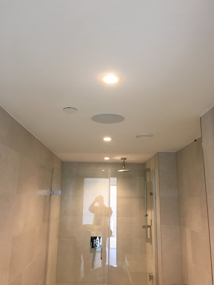Shot of bathroom with Klipsch in-ceiling speakers and shower with glass screen