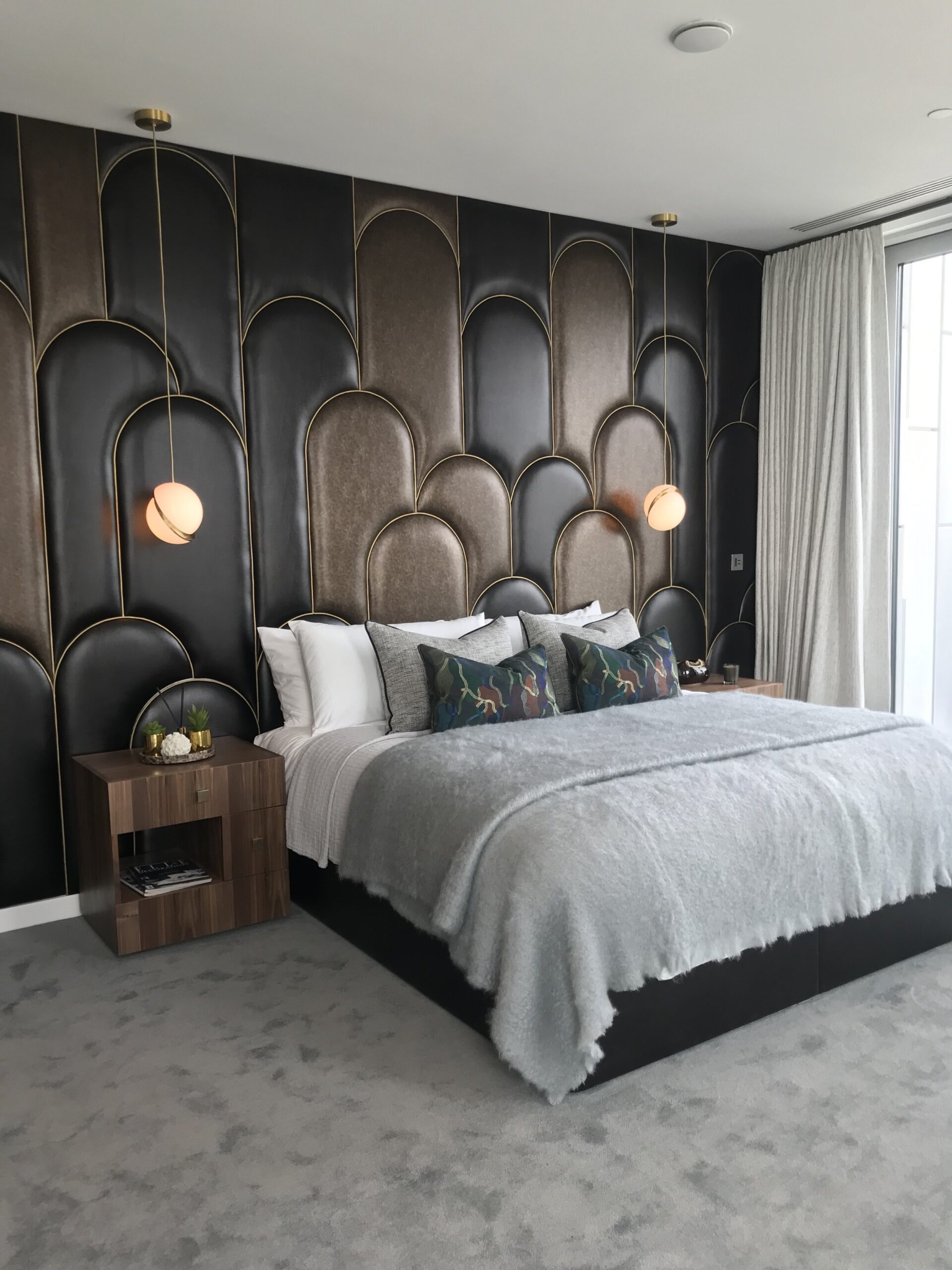 Bedroom with double bed, leather feature wall and low hanging pendant either side of the bed
