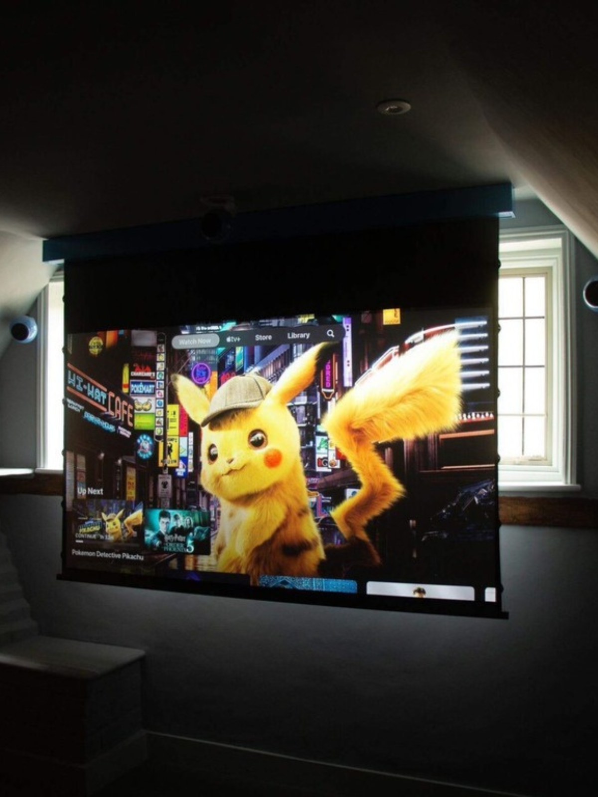 Projector screen with Pokemon movie projected and blue Gallo speakers either side of the screen