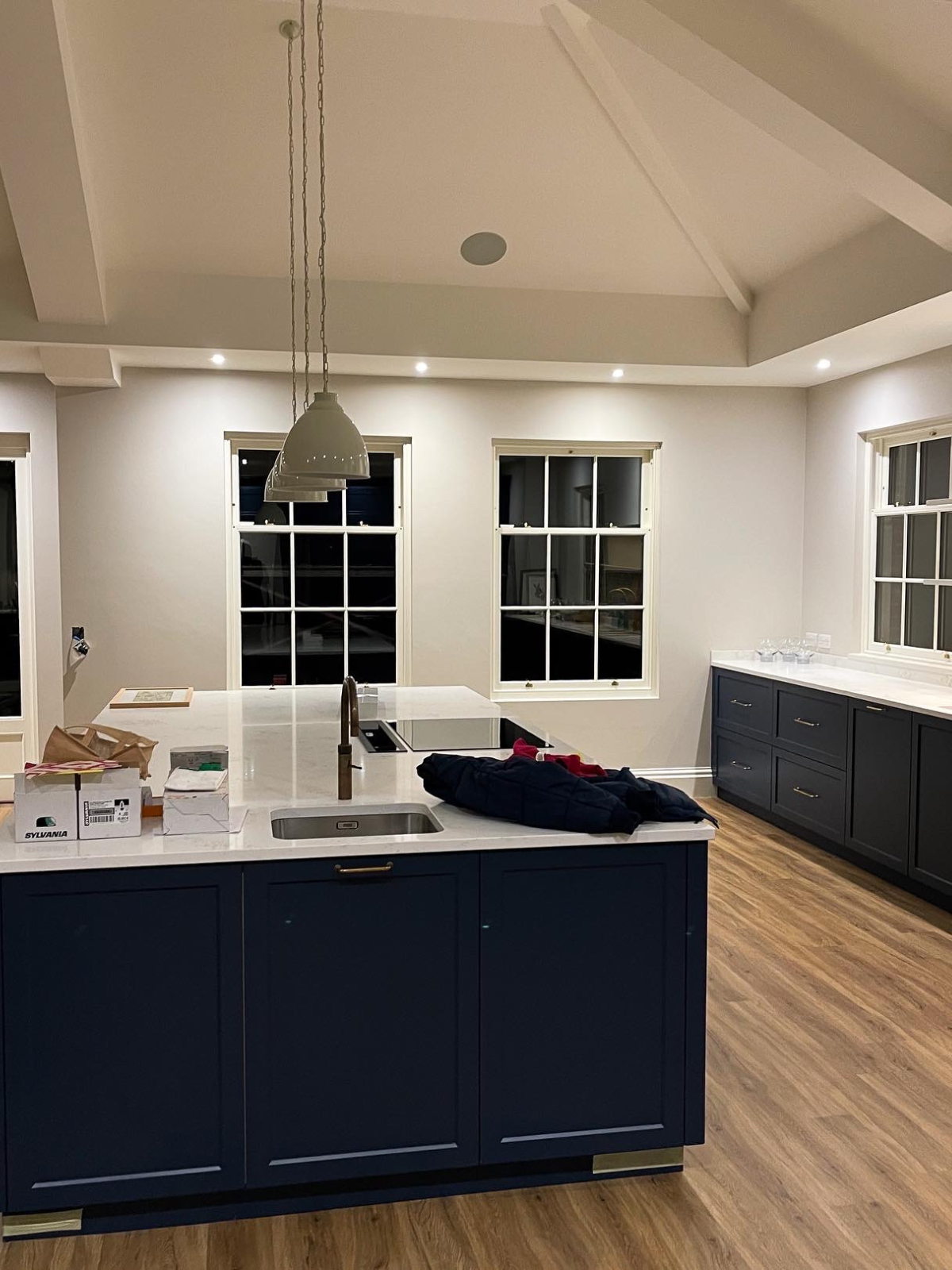 Kitchen with navy blue island, pendant lighting and in-ceiling speakers